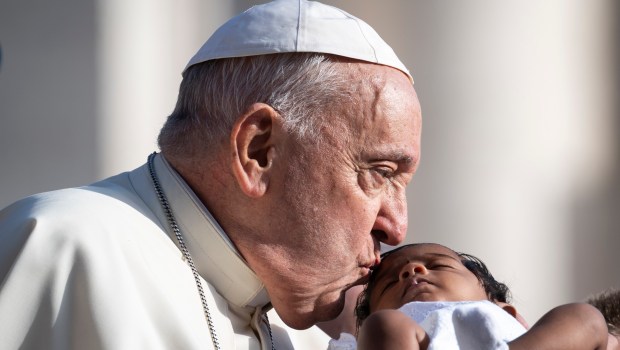 Pope Francis kisses a child as he arrives for his weekly general audience in St. Peter's Square at the Vatican on August 28, 2024