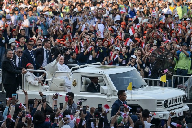 Pope Francis waves to worshippers gathering at Madya stadium on his way to attend the holy mass at the Gelora Bung Karno Stadium in Jakarta on September 5, 2024.