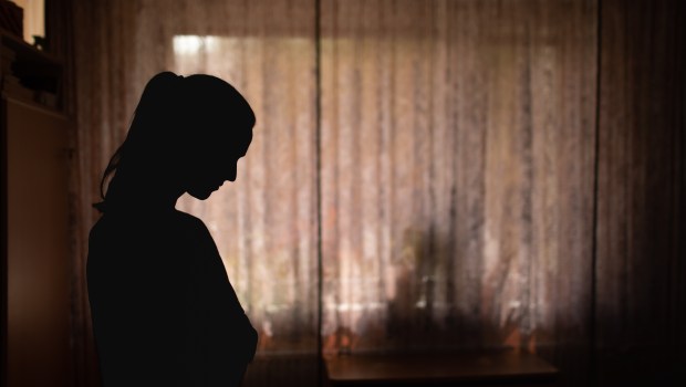 Przygnębiona kobieta w zaciemnionym pokoju