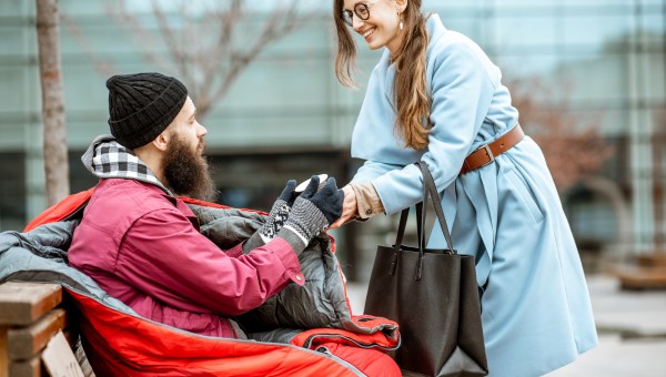 Une jeune femme aide un homme sans-abri