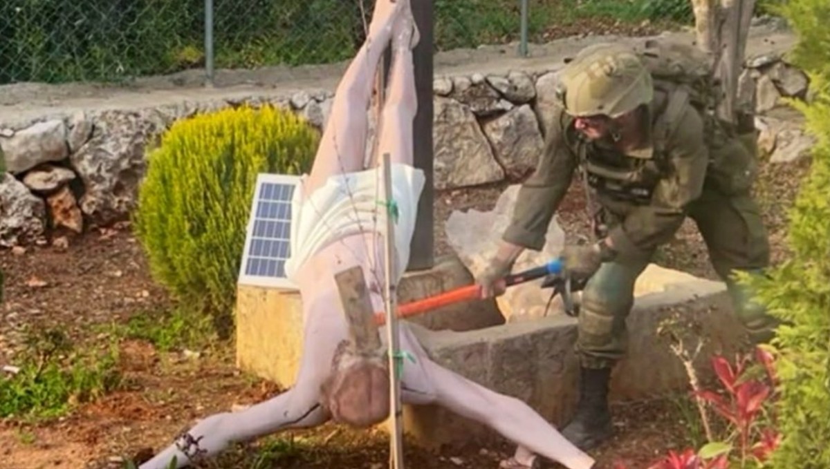 Un soldat israélien profane une représentation de Jésus en croix lors d'opérations dans le sud du Liban.