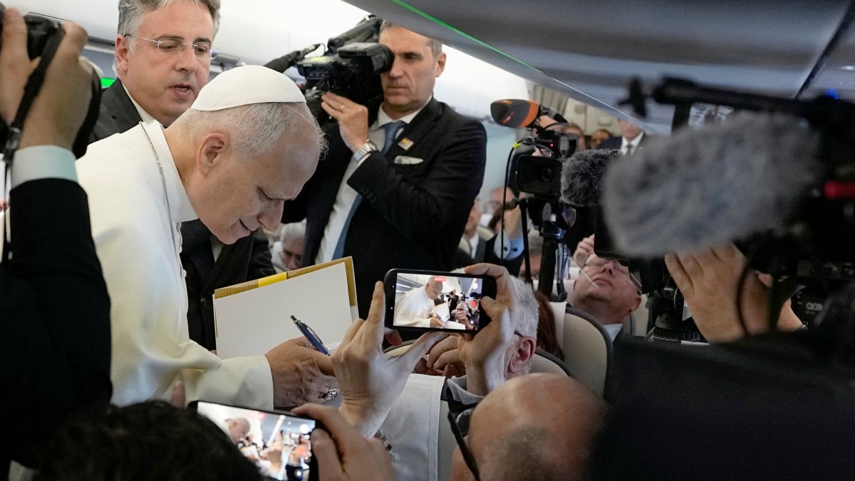 Pope Leo XIV signs autographs to journalists aboard the plane carrying him to Madrid on June 6, 2026